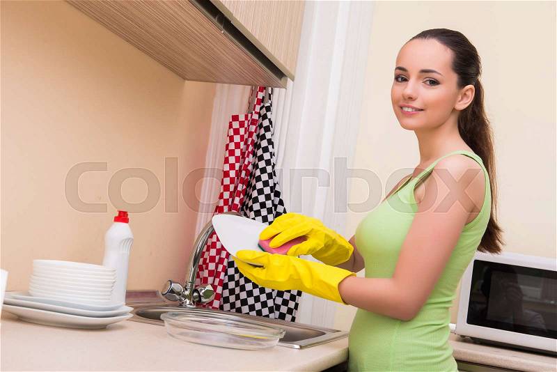 Young wife woman washing dishes in kitchen, stock photo