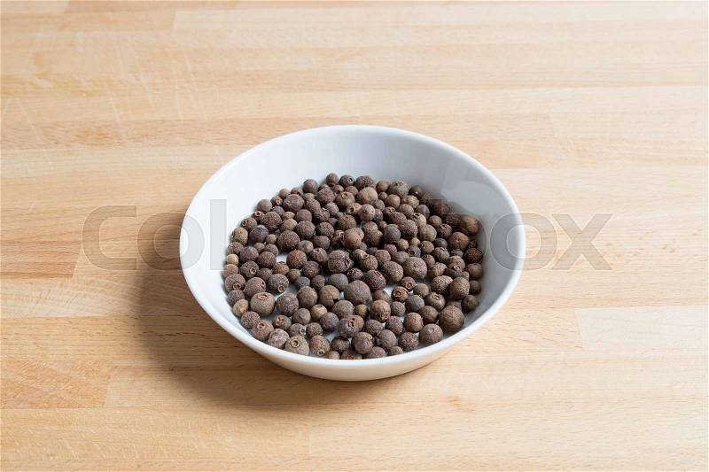 Allspice in a bowl on wood, stock photo