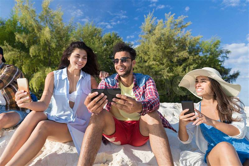 Young People Group On Beach Using Cell Smart Phone Summer Vacation, Happy Smiling Friends Chatting Online Holiday Travel, stock photo