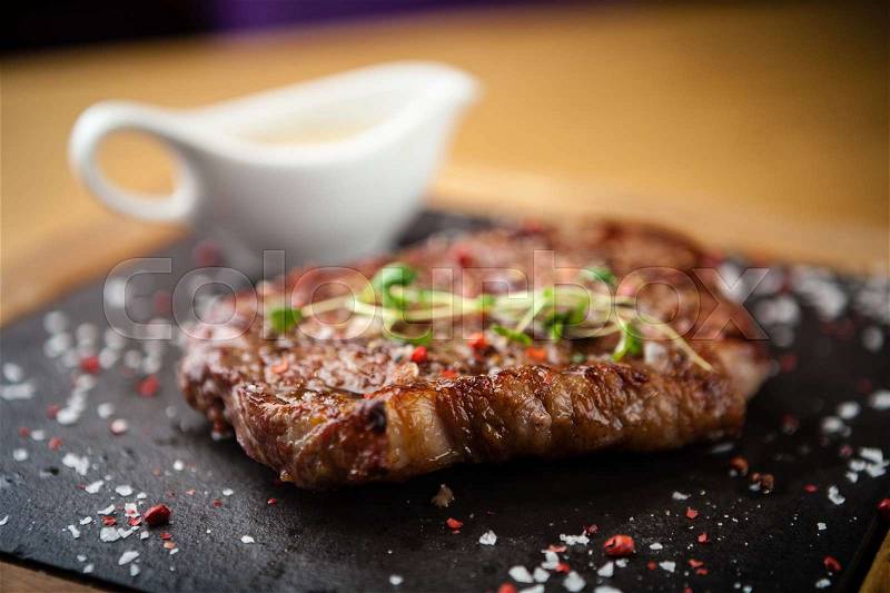 Prime Black Angus New York strip steak served on a warm stone board, stock photo