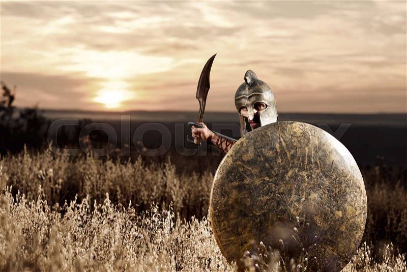 Sepia toned shot of a brave fearless Spartan warrior in a battledress attacking with his sword copyspace Greek warrior armed with a sword and shield on the battlefield fighter hero confidence concept, stock photo