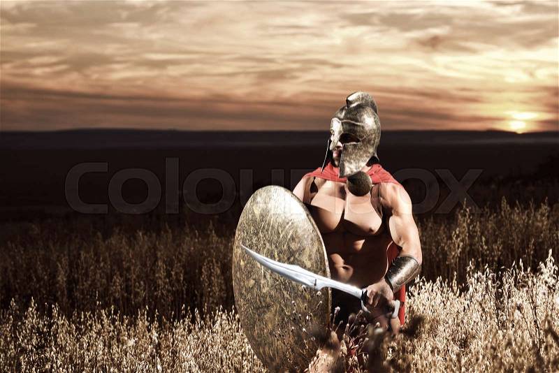Sepia toned shot of a medieval Spartan warrior in a battledress walking through the battlefield armed with his sword and a shield copyspace protection safety guard security bravery hero concept, stock photo