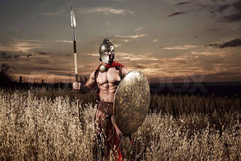 Calm but dangerous. Sepia toned shot of a legionary national roman warrior in ancient battledress standing in the field looking away armed with spear protection security guardian hero historical , stock photo