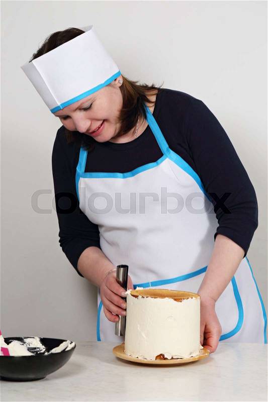Confectioner preparing cake. Chef covers cream cake, stock photo