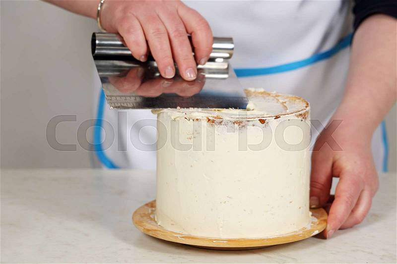 Confectioner preparing cake. Chef covers cream cake, stock photo