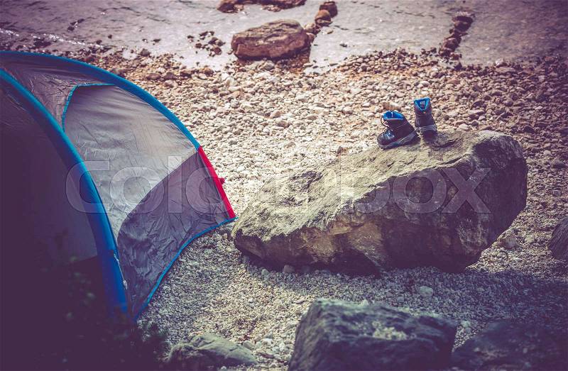 Lake Camping Scenery. Campsite on the Rocky Lake Shore. Outdoor and Recreation Theme. Wet Shoes on the Boulder, stock photo