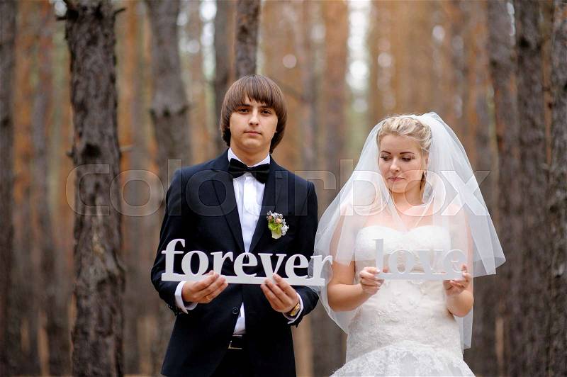 Bride and groom holding wooden letters love forever, stock photo