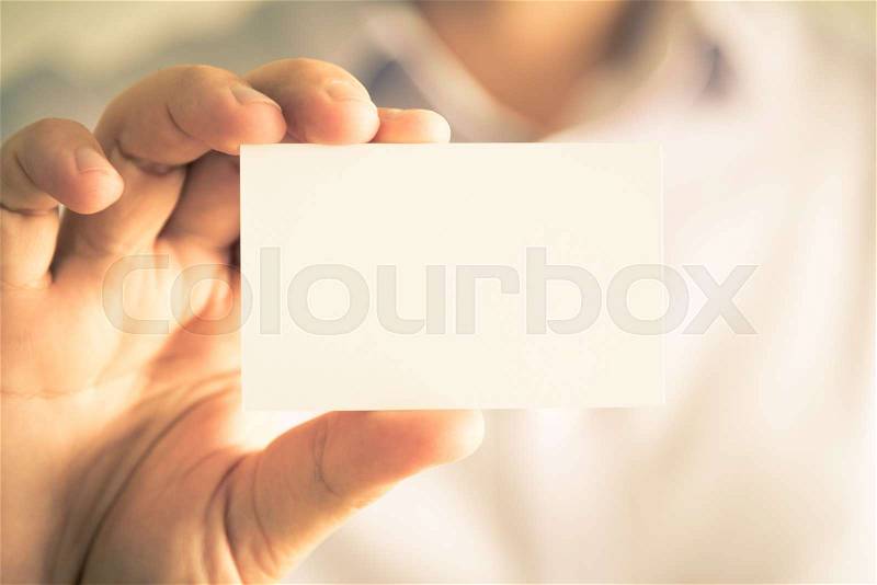 Closeup on businessman holding white empty message card with copy space for text, business concept image with soft focus background and vintage tone, stock photo