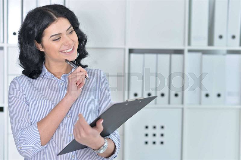 Youn beautiful woman making notes using clipboard, stock photo
