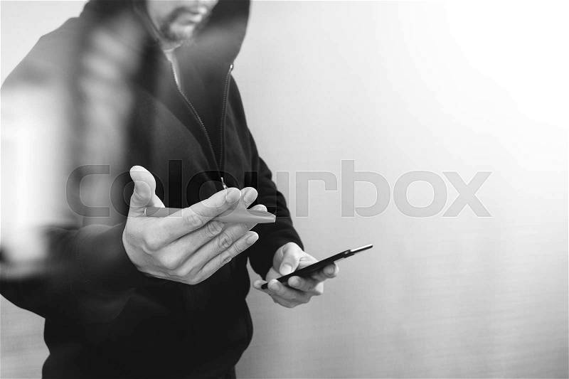 Hipster male in a hood hand using mobile phone payments online shopping,omni channel,front view,black and white, stock photo