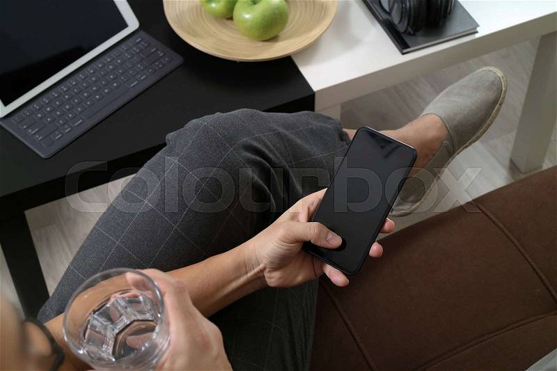Hipster hand using smart phone for mobile payments online business,glass of water,sitting on sofa in living room,green apples in wooden tray,graphic interfce icons virtual screen, stock photo