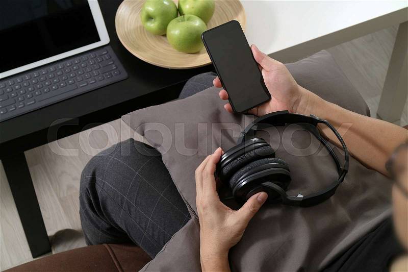 Hipster hand using smart phone for mobile payments online business,headphone,sitting on sofa in living room,green apples in wooden tray, stock photo