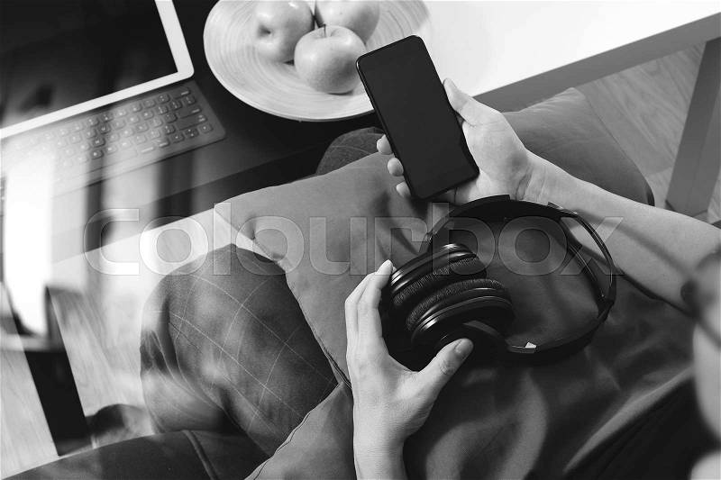 Hipster hand using smart phone for mobile payments online business,headphone,sitting on sofa in living room,green apples in wooden tray,graphic interfce icons virtual screen,black white, stock photo