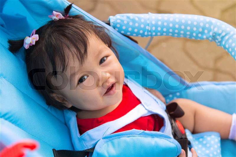 Baby girl smile sitting in stroller, childhood and people concept, stock photo