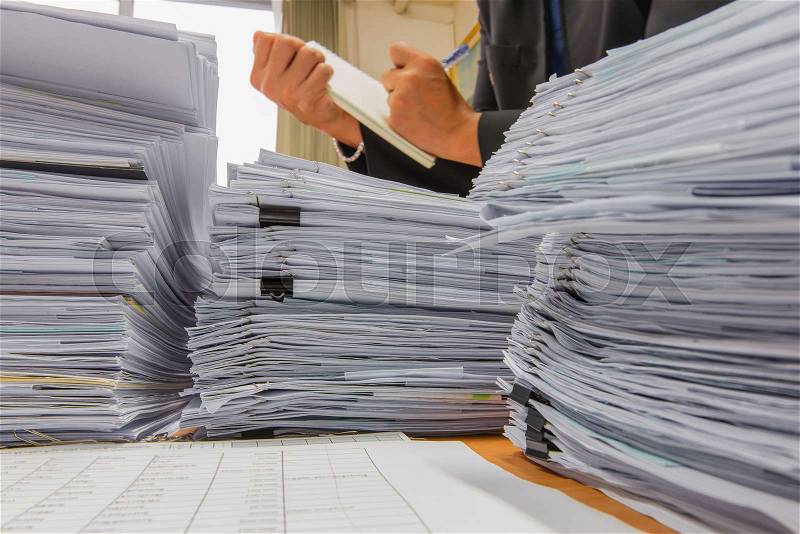 Documents on desk stack up high waiting to be managed, stock photo