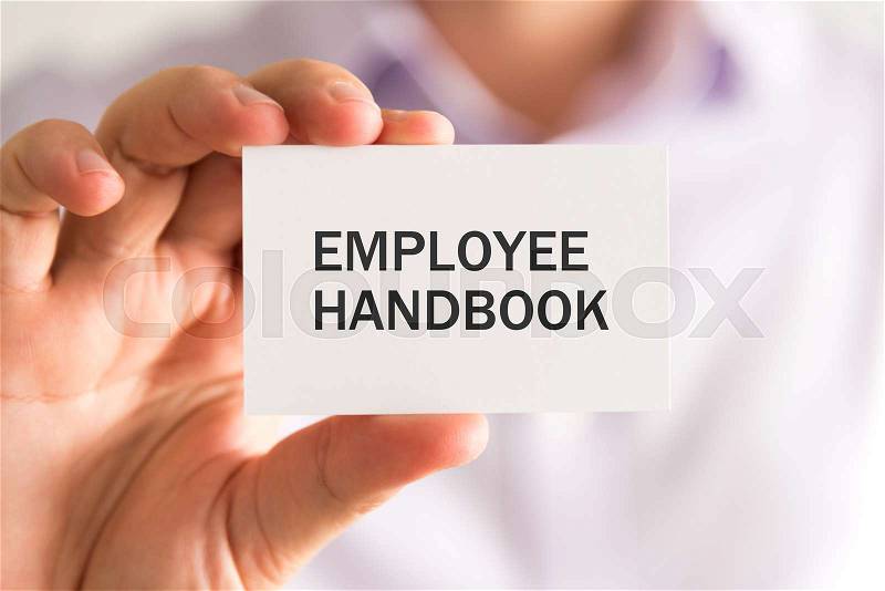 Closeup on businessman holding a card with EMPLOYEE HANDBOOK message, business concept image with soft focus background and vintage tone, stock photo