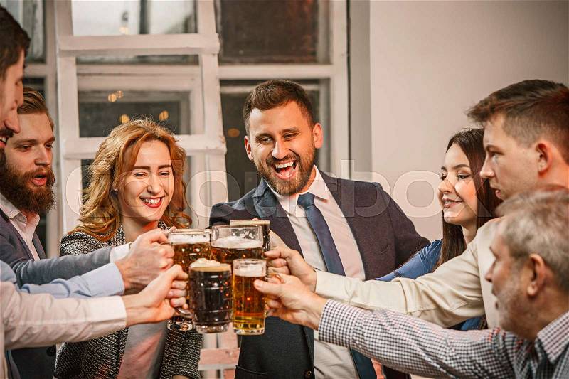 Group of friends enjoying evening drinks with beer on wooden table, stock photo