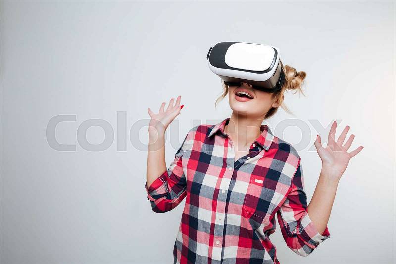 Happy Woman in shirt using virtual reality device in studio. Isolated gray background, stock photo