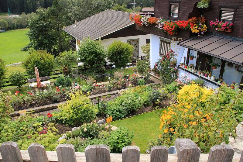Wonderful backyard with blooming plants and potted plants on the balcony in the village Heiligenblut in Austria in the summer, stock photo