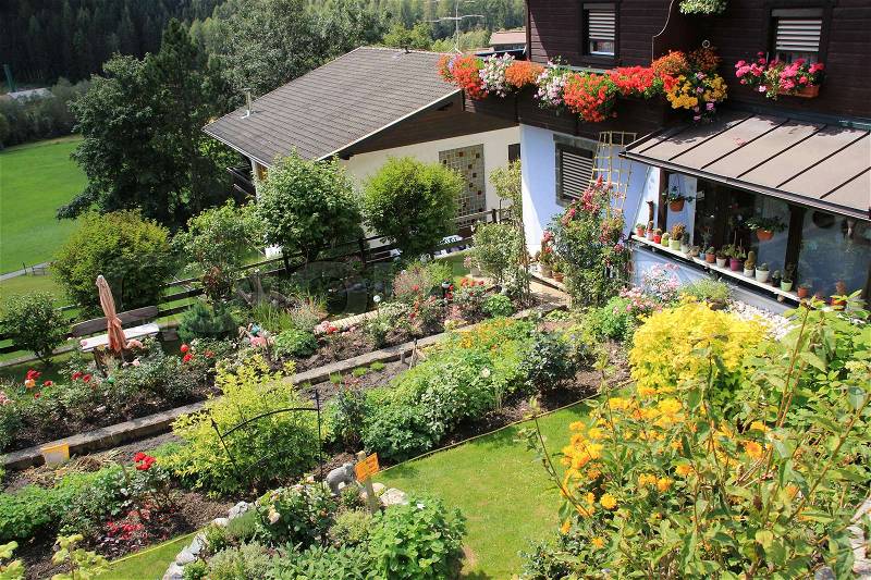 Wonderful backyard with blooming plants and potted plants on the balcony in the village Heiligenblut in Austria in the summer, stock photo