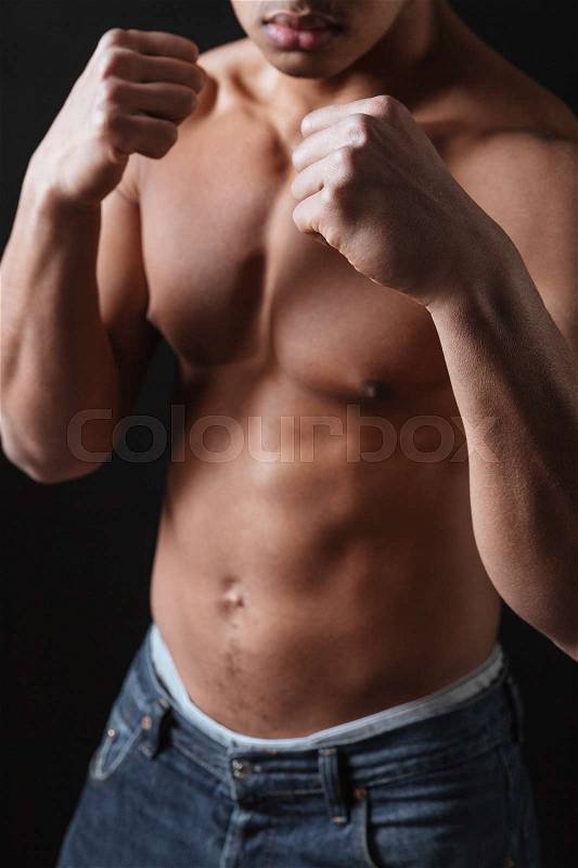Cropped picture of attractive young african man boxer posing over black background, stock photo