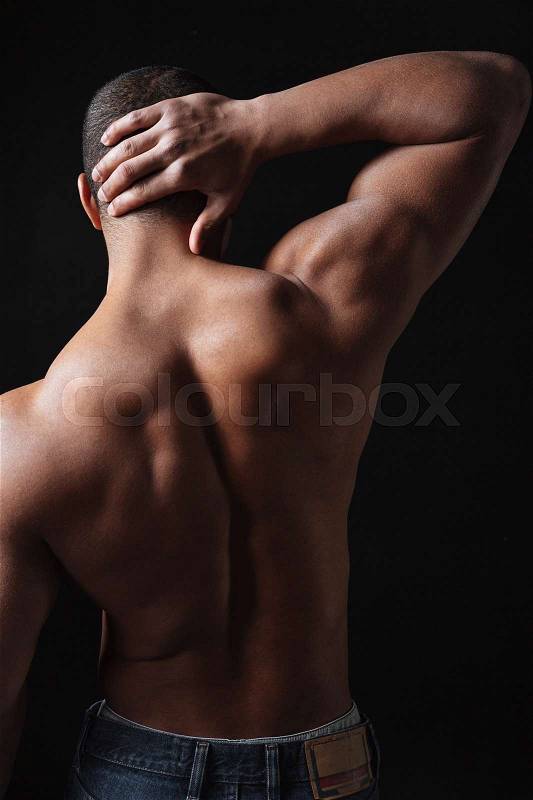 Back view photo of young african sportsman posing over black background, stock photo