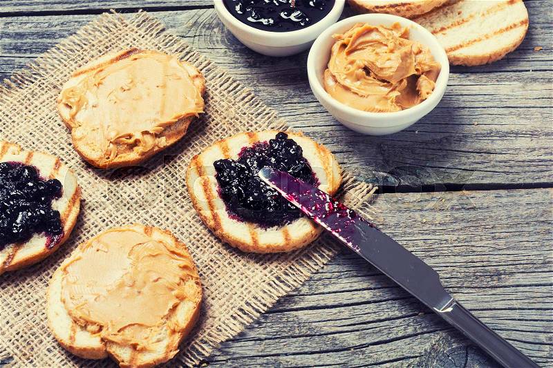 Peanut butter and jam sandwich on rustic wooden background, stock photo