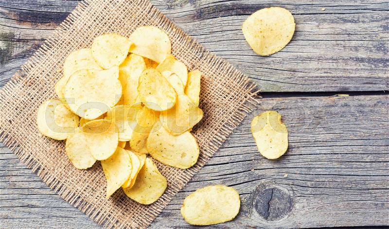 Crispy potato chips on old wooden background . Top view, stock photo