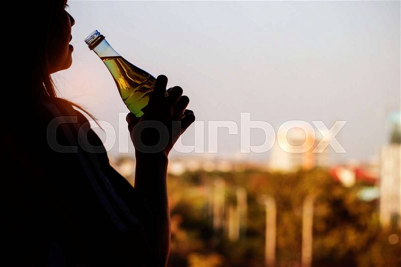 Woman drinking water after exercising in the evening, stock photo