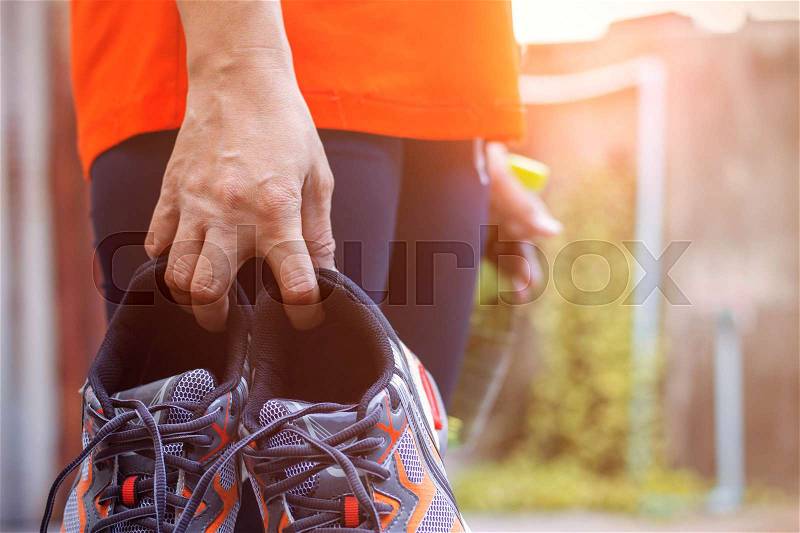 Woman holding shoes and drinking water for exercise, stock photo