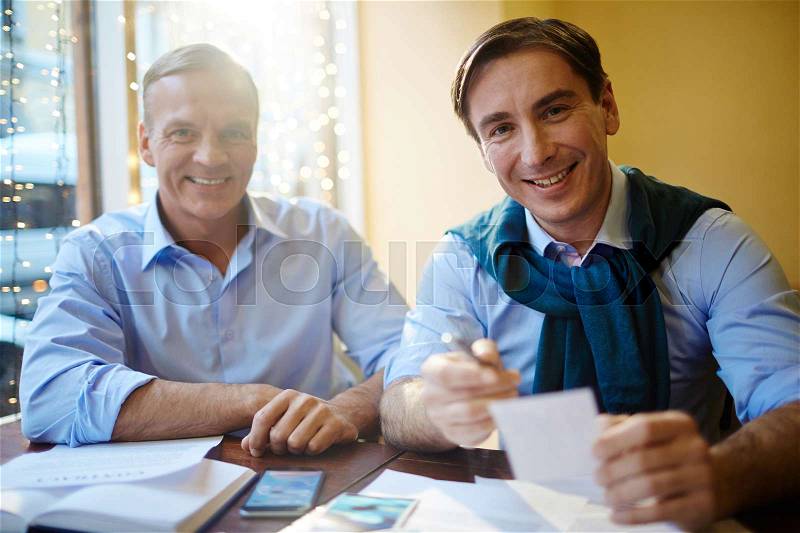 Happy businessmen looking at camera while working, stock photo