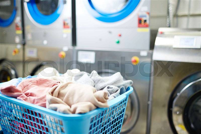 Basket with clothes in laundromat, stock photo