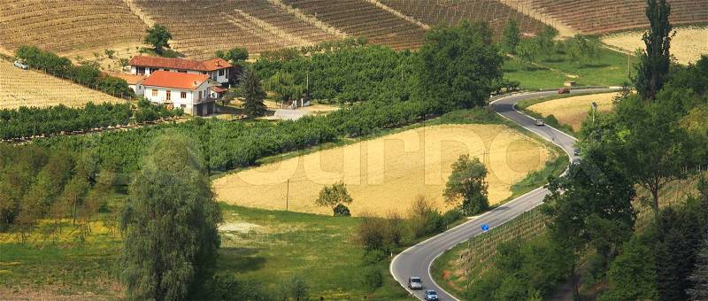 Panoramic view on lone house and serpentine road among hills of Piedmont, northern Italy, stock photo