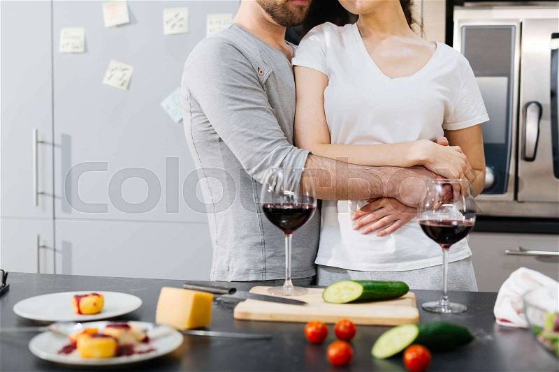 Young man embracing his wife by dinner table, stock photo
