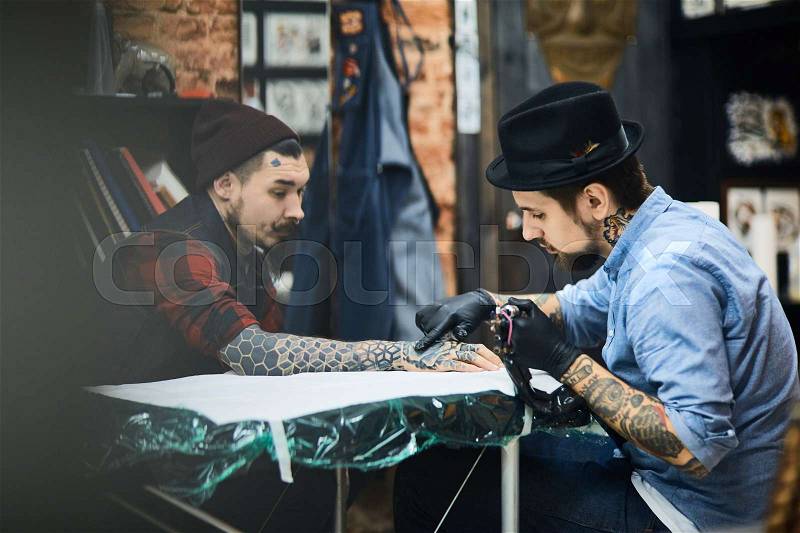 Master of tattooing and his client in salon, stock photo