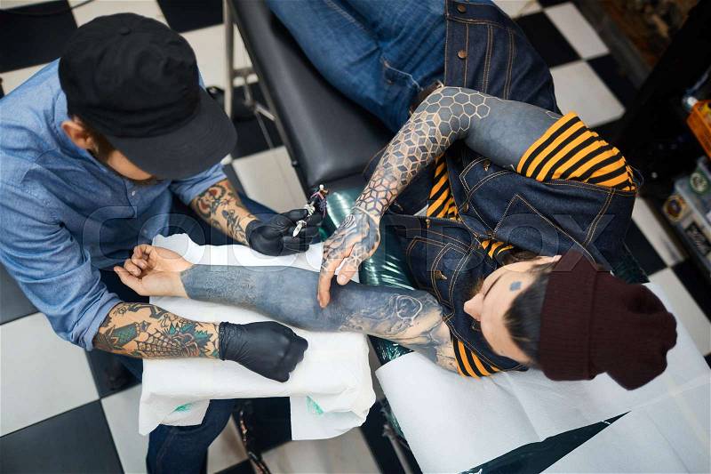 Client explaining his master his tattoo preferences, stock photo