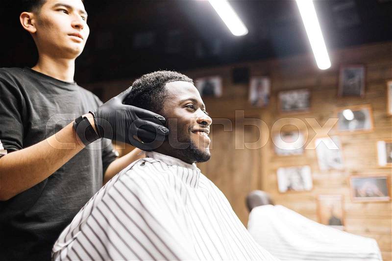 Happy man looking in mirror in barbershop, stock photo