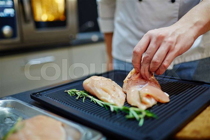 Chef taking raw chicken tenderloin, stock photo