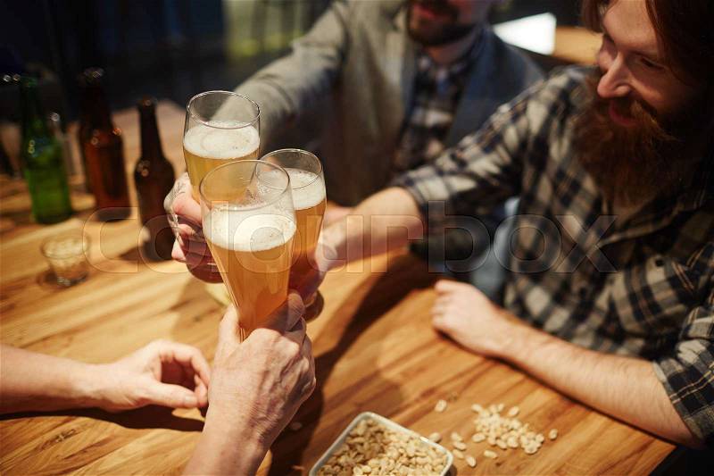 Bearded buddies toasting with beer in pub, stock photo