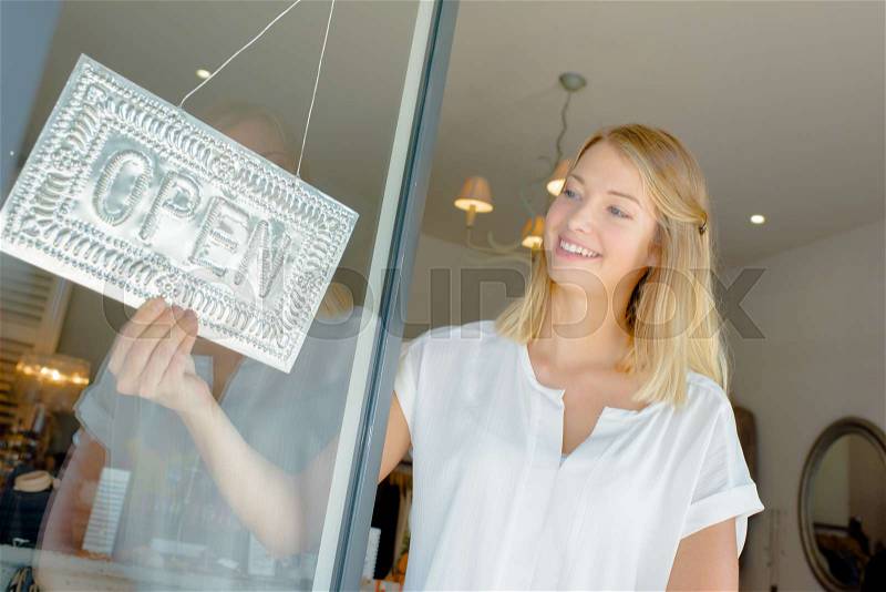 Lady turning shop sig to open, stock photo