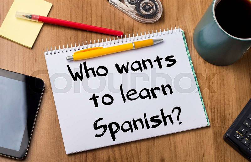 Who wants to learn Spanish? - Note Pad With Text On Wooden Table - with office tools, stock photo