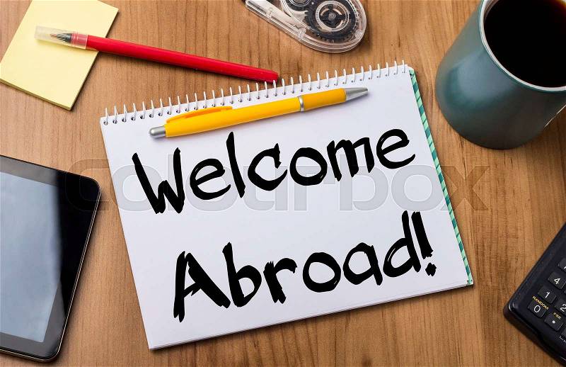 Welcome Abroad! - Note Pad With Text On Wooden Table - with office tools, stock photo