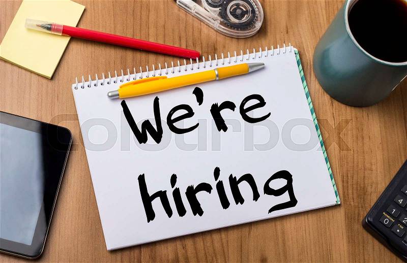 We’re hiring - Note Pad With Text On Wooden Table - with office tools, stock photo