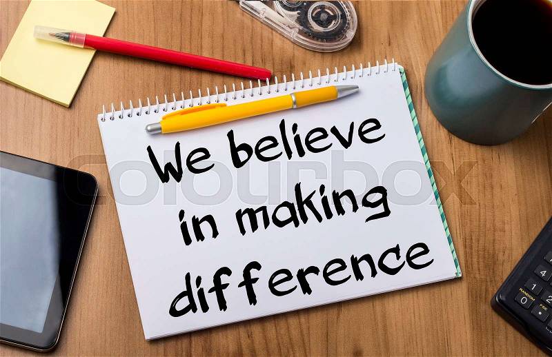 We believe in making difference - Note Pad With Text On Wooden Table - with office tools, stock photo