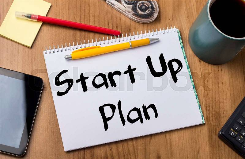 Start Up Plan - Note Pad With Text On Wooden Table - with office tools, stock photo