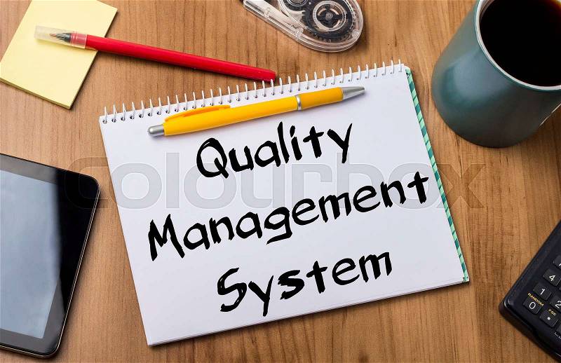 Quality Management System QMS - Note Pad With Text On Wooden Table - with office tools, stock photo
