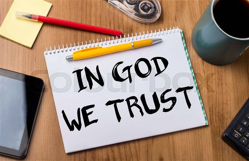 IN GOD WE TRUST - Note Pad With Text On Wooden Table - with office tools, stock photo