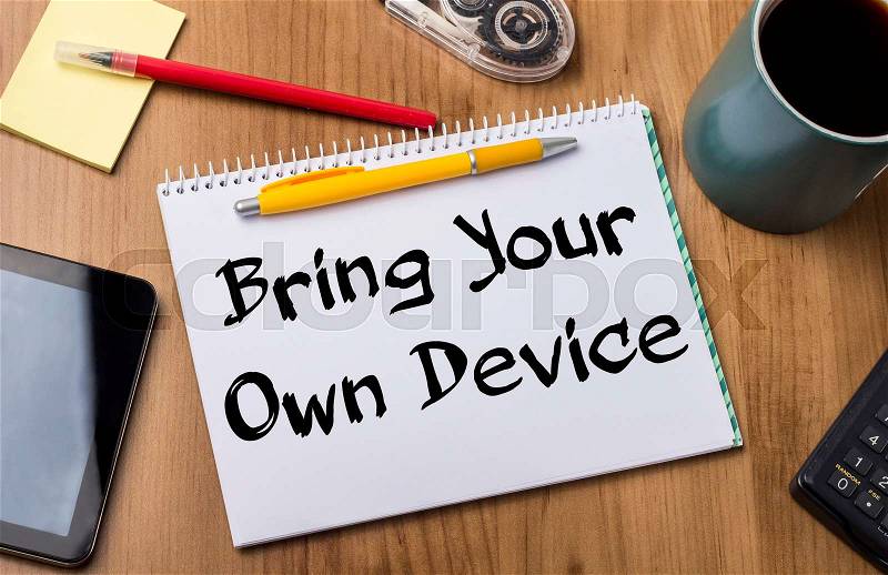Bring Your Own Device BYOD - Note Pad With Text On Wooden Table - with office tools, stock photo