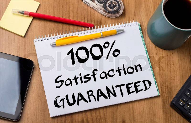 100% Satisfaction GUARANTEED - Note Pad With Text On Wooden Table - with office tools, stock photo