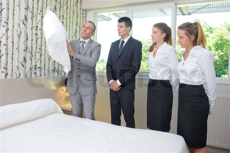 Hotel staff watching supervisor with pillow, stock photo
